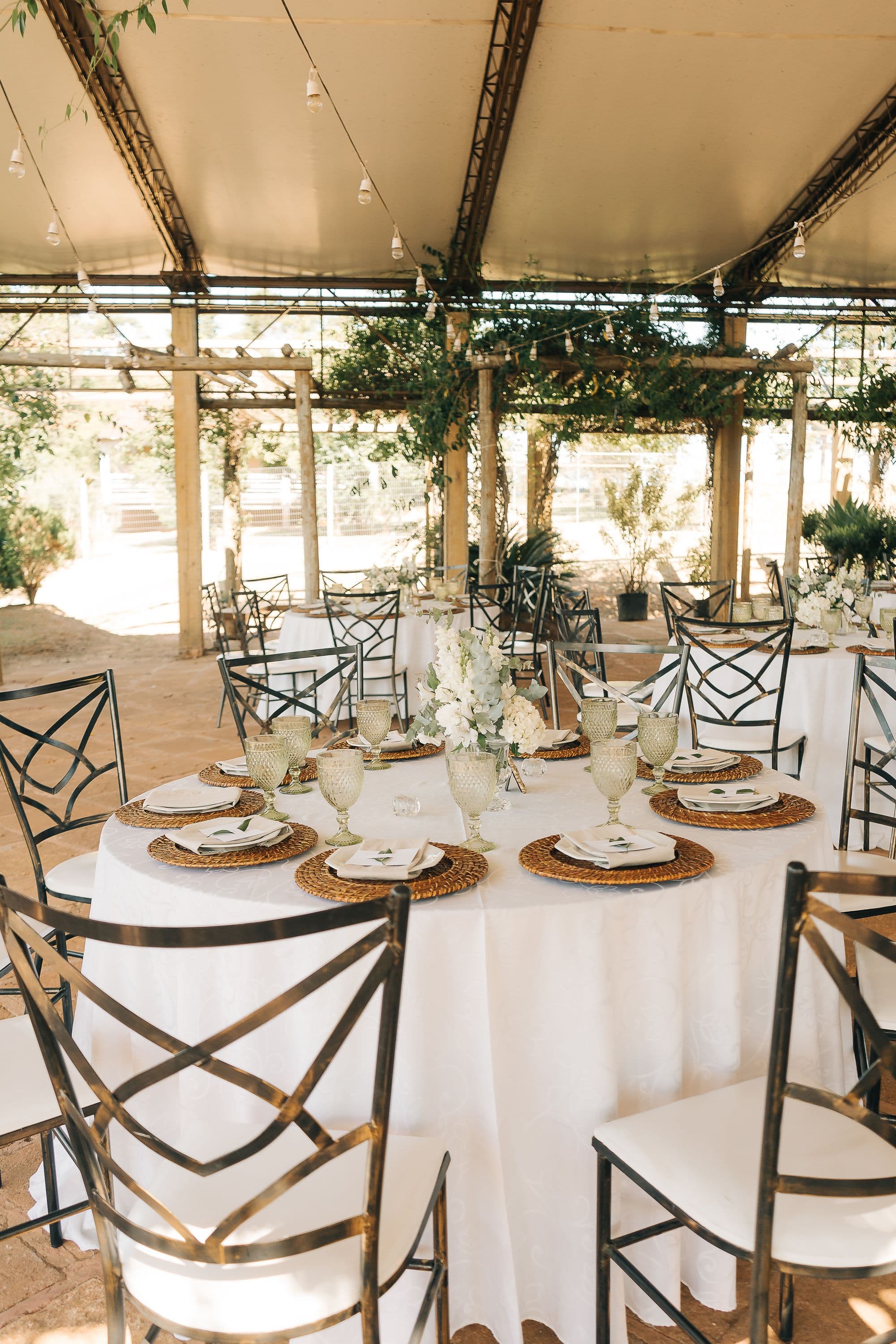 An outdoor wedding reception set for dinner under a canopy